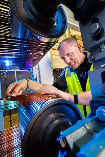 A worker examining machinery at a carbon fibre manufacturing plant.