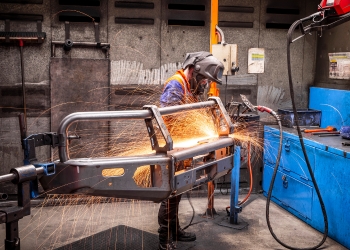 Person in welding a piece of metal wearing a welding mask with sparks flying