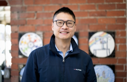 Jack Zhou smiling, wearing a blue jumper