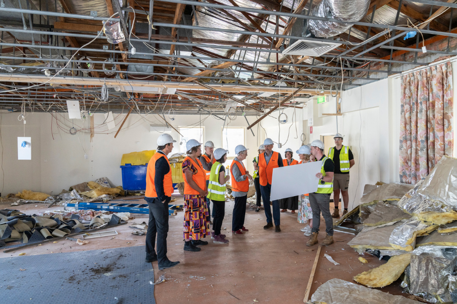 A group of people wearing safety gear, including high-visibility vests and hard hats in a building's interior that is under renovation.