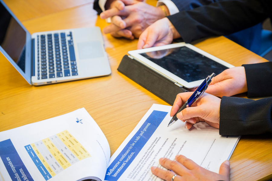 View of an office desk with a document opened to a page that says 'Melbourne continues to be a safe and proven investment location'