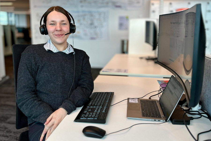 Liam Jones sits next to computer desk with headset.