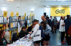 Crowd looking through shelves of records and a yellow sign in the background that reads independent music exchange