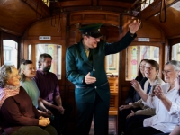 Tram conductor standing and talking to seated passengers on tram