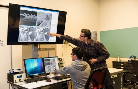 Two people are looking at at multiple screens 