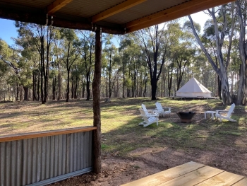 Image looking out at a glamping tent and chairs set up near a fire pit