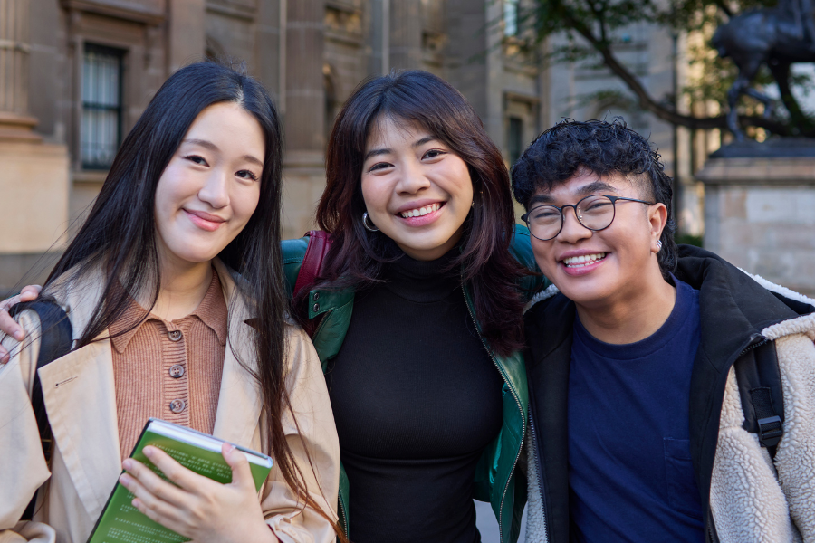 3 international students looking at camera in a university setting