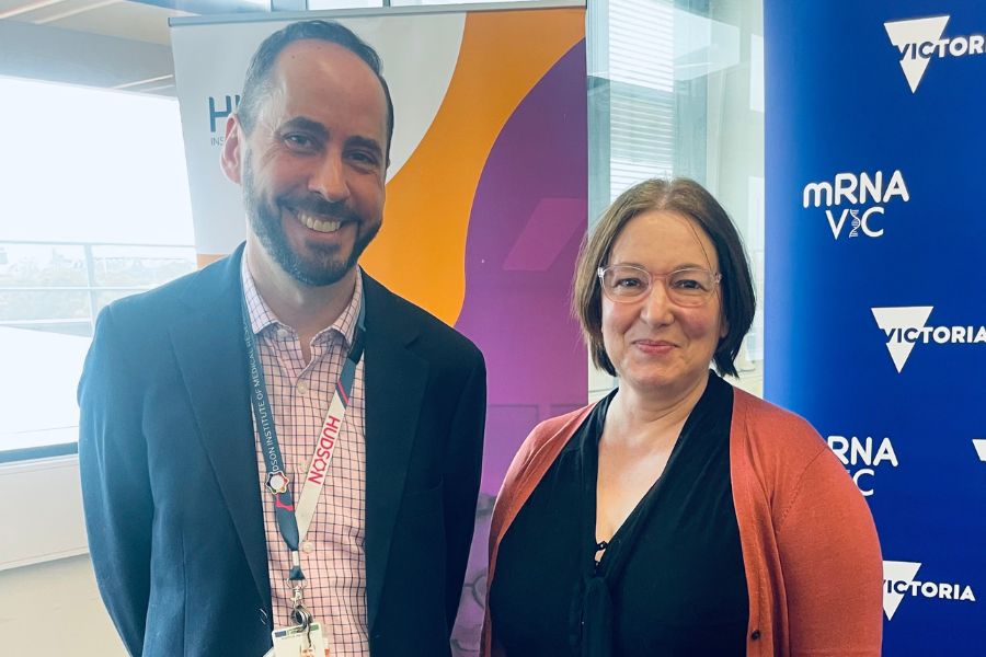 Associate Prof Michael Gantier from the Hudson Institute with lupus patient Camille McBride standing in front of banners promoting MRNAVIC
