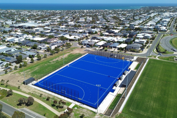 Birds-eye view of the new hockey pitch surrounded by residential buildings with the ocean's horizon in the background.