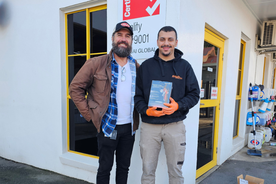Sahin standing holding certificate at a worksite