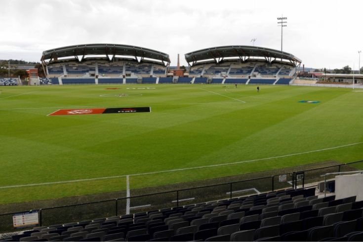 A football oval with lush grass and 2 new grandstands in the background.