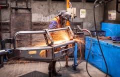 Person in welding a piece of metal wearing a welding mask with sparks flying