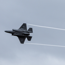 Defence aircraft flying against an overcast sky