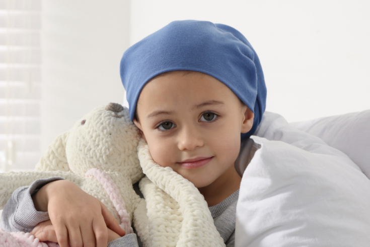 Child with hair covered holding crocheted toy