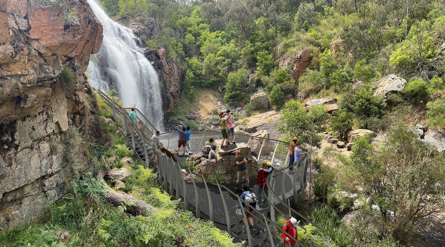 Render of path of viewing platform by a waterfall with people standing on it 
