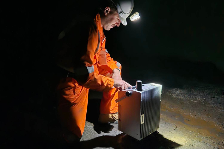 A scientist in high-vis underground with flashlight focused on Nomad Atomic's quantum sensor