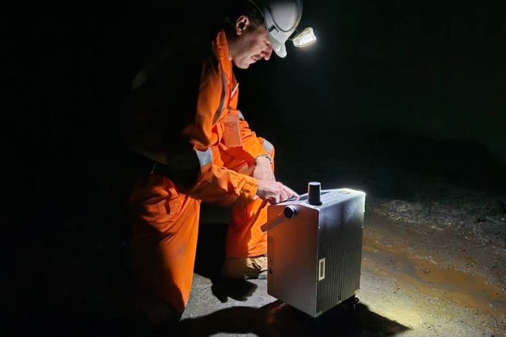 A scientist in high-vis underground with flashlight focused on Nomad Atomic's quantum sensor