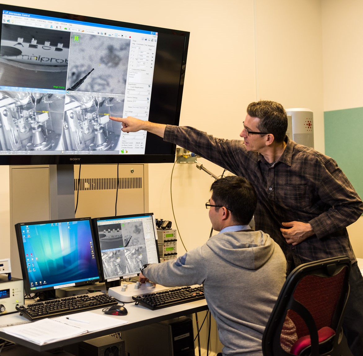 Two people are looking at at multiple screens 