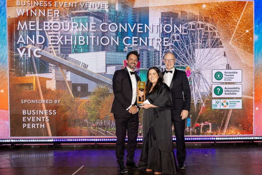 Melbourne Convention and Exhibition Centre winners of Business Event Venues The image shows 3 individuals in formal attire posing with an award on a stage. Behind them is a backdrop featuring a cityscape and a sign that reads "Business Event Venue Winner Melbourne Convention and Exhibition Centre, VIC."