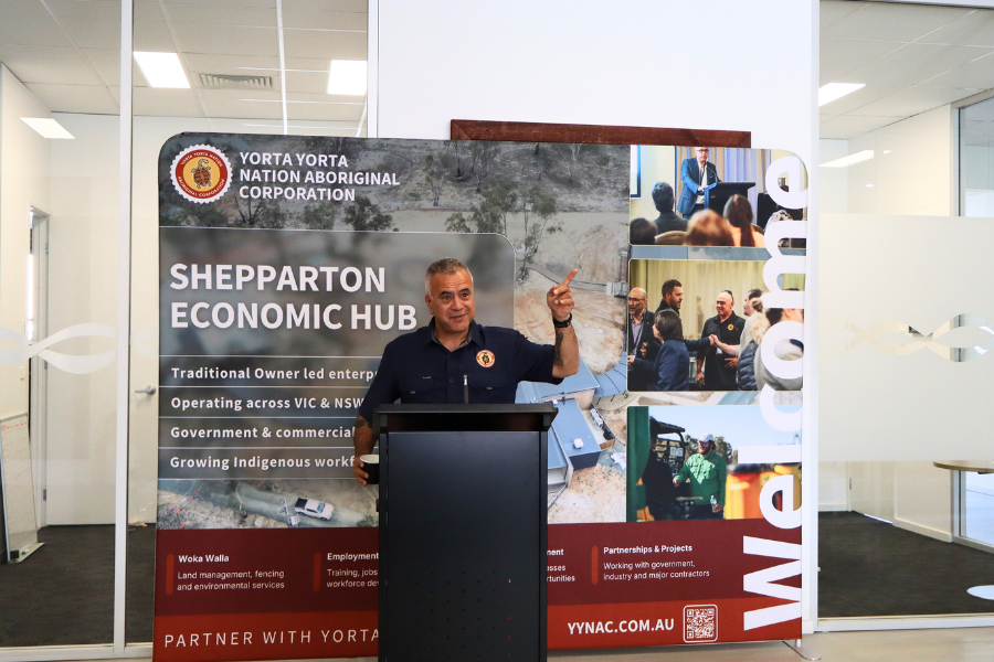 Presenter welcoming guests at podium inside new economic hub. Banner behind reads Shepparton Economic Hub