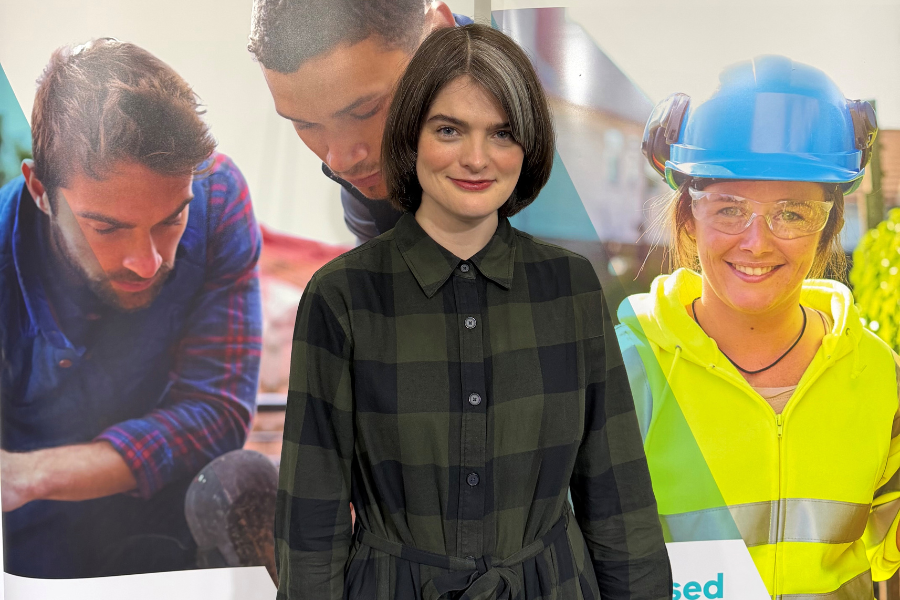 Alex standing in front of an Apprenticeships Victoria promotional banner