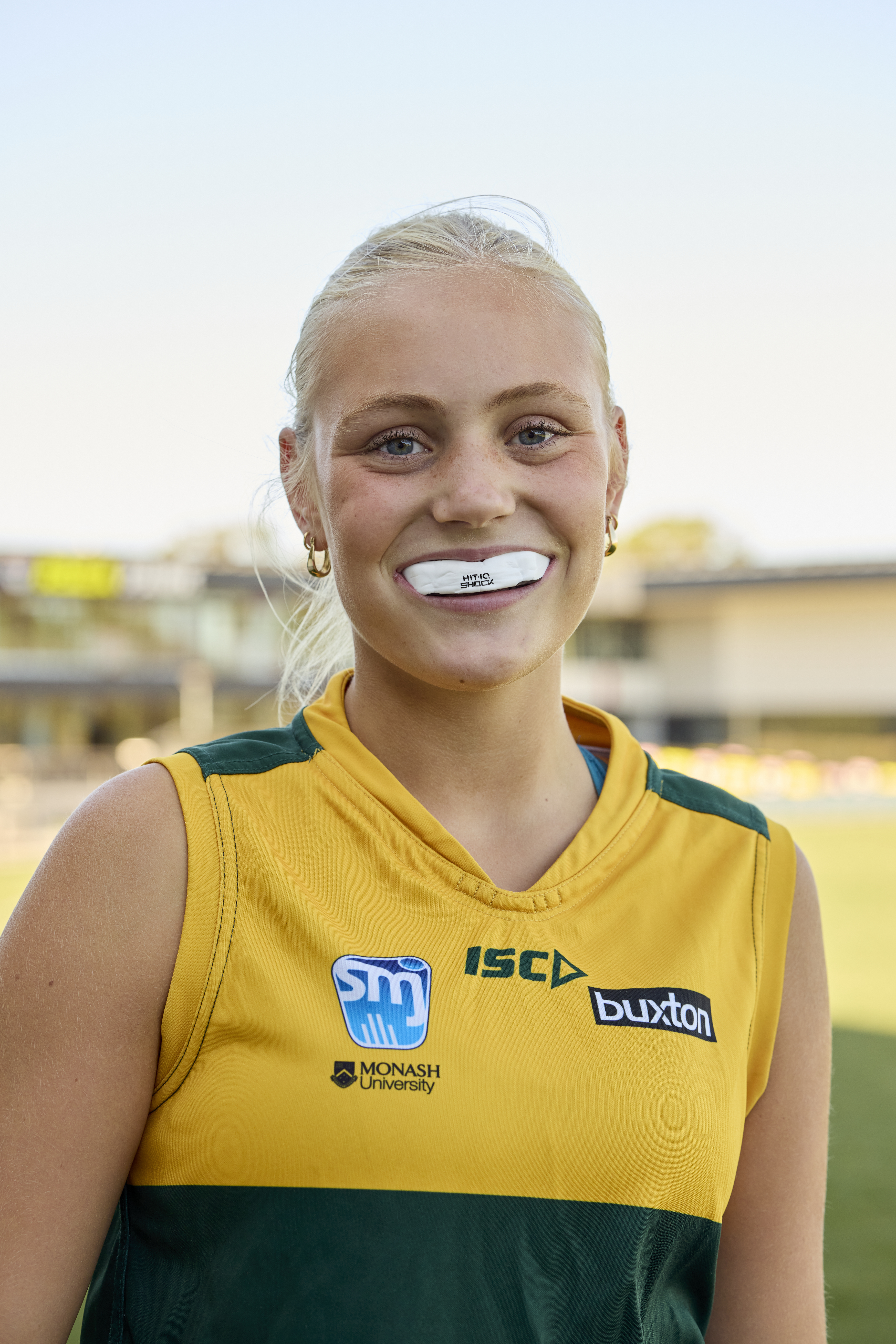 A sportsperson is facing the camera and showing a white mouthguard