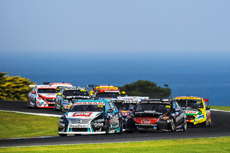 Supercars sports cars racing around a bend with ocean in background