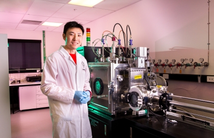 Scientist in lab coat and gloves standing in a laboratory with advanced equipment