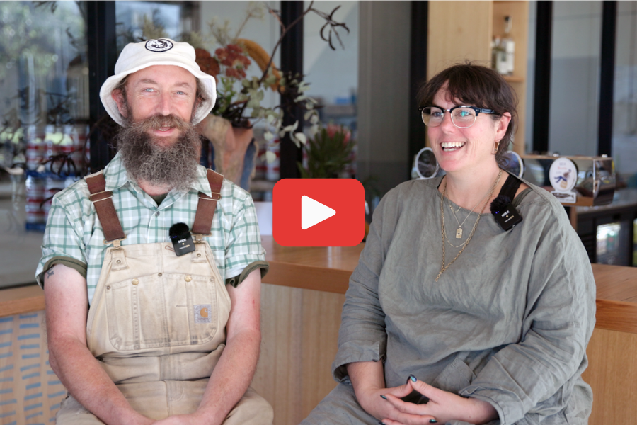Sailors Grave owners Chris and Gab Moore sitting in their Brewery talking to camera with play button.