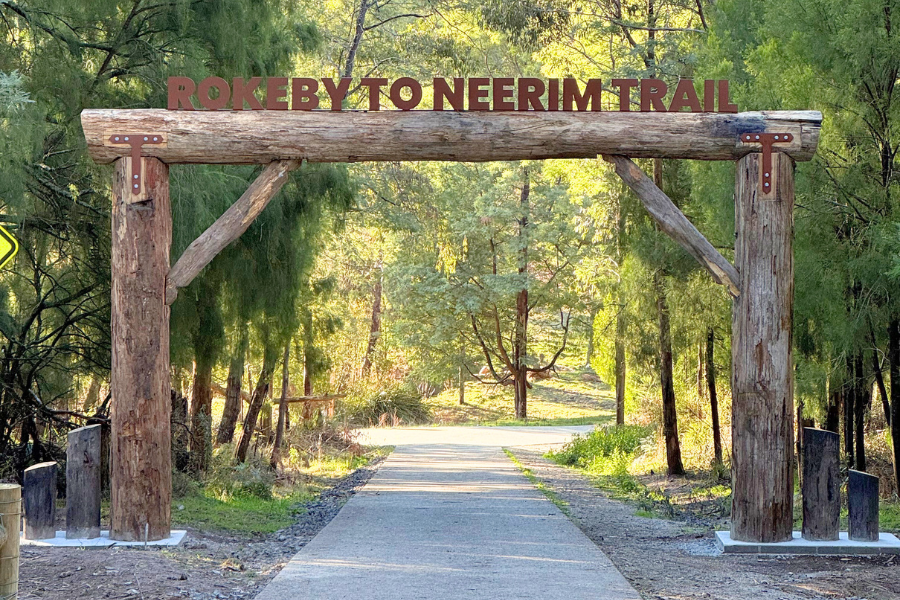 A wooden structure over a path through trees with the words Rokeby to Noojee Trail