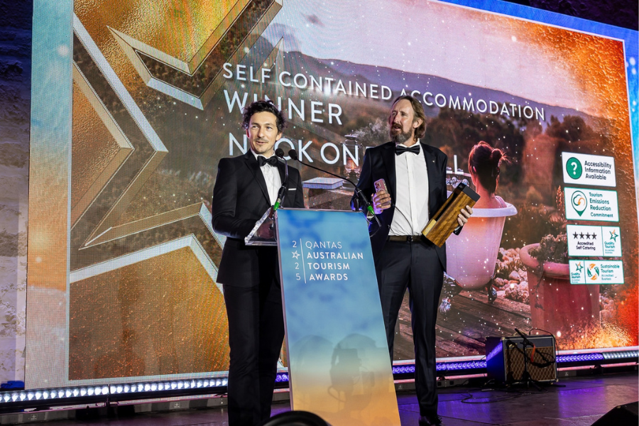 Nook On The Hill in Halls Gap winners of Self-Contained Accommodation The image shows two individuals in formal attire on stage at an awards ceremony. The individuals are accepting award for Nook On The Hill in Halls Gap winners Self-Contained Accommodation.