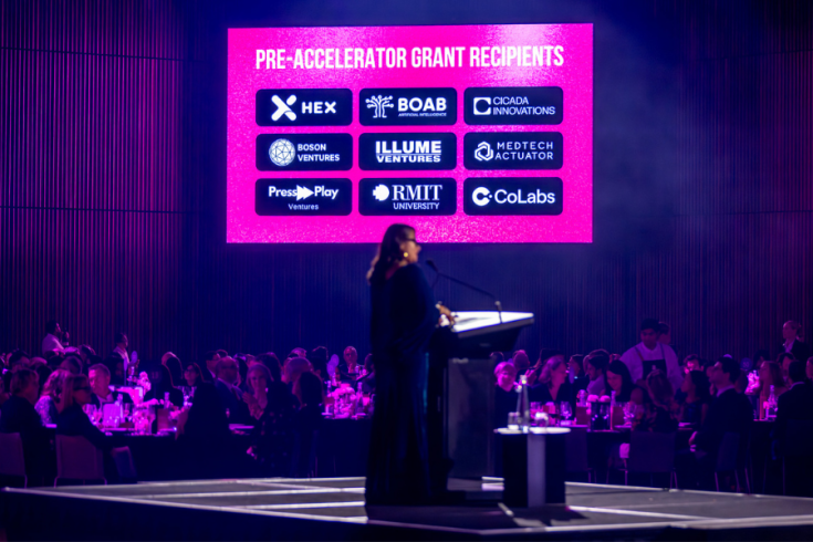 A person in front of a lectern presenting to a room of people