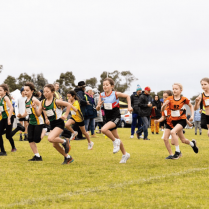 Children participating in a cross-country race on a grassy field.