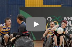 People playing wheelchair rugby with video play button in the centre