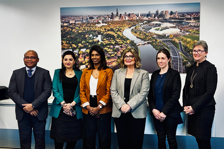 The 6 industry leaders appointed standing in front of a large aerial photo of Melbourne, smiling at the camera.