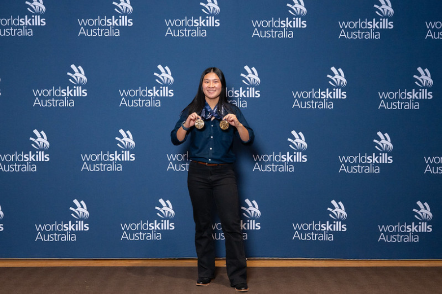 lily-Grace Toohill holding medals infront of the Worldskills Australia branding