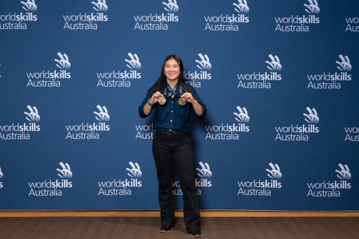 lily-Grace Toohill holding medals infront of the Worldskills Australia branding