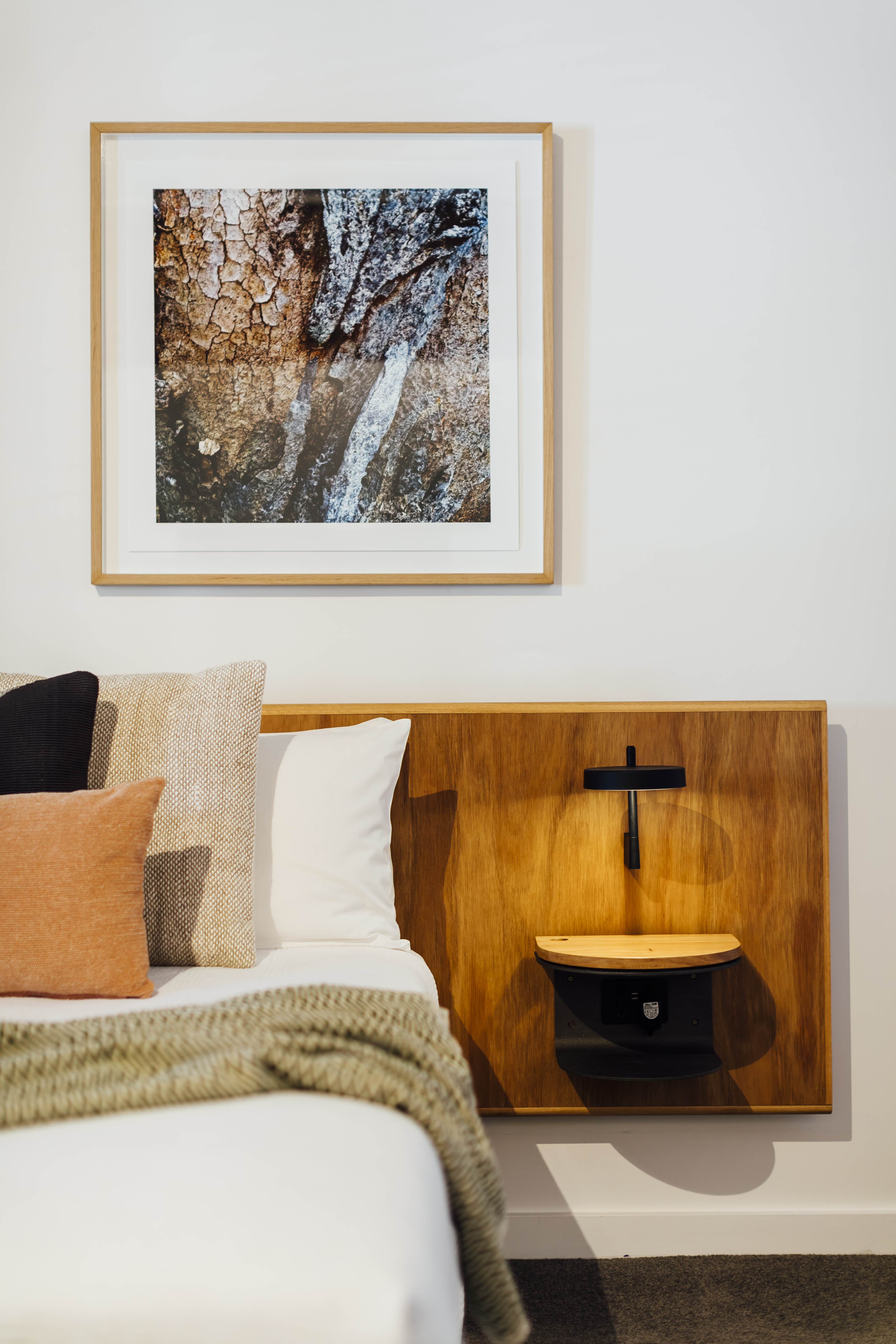 A cozy bedroom corner featuring a bed with assorted pillows and a knitted thro