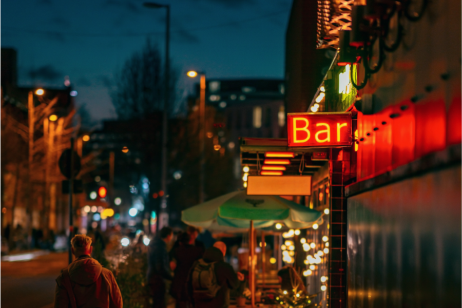 A dimly lit street showing a bars and restaurants