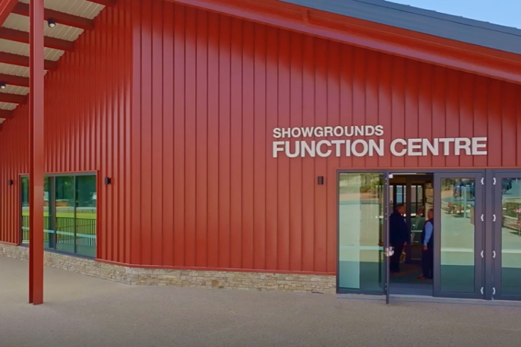 External entrance to the Showgrounds Function Centre, red steel building with high arching roof.