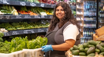 A female staff member holding a box of lettuce in the supermarket
