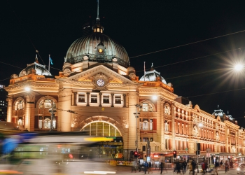 Exterior of Flinders street station lit up with lights on a dark night