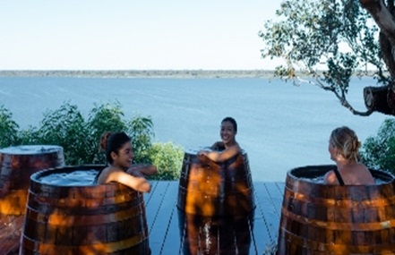 Image of three women in a wooden tub overlooking scenery