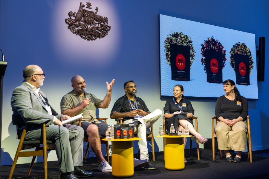 Panel discussion at the expo with 4 speakers seated on stage, engaging in conversation, with background screens and the Australian Government emblem.