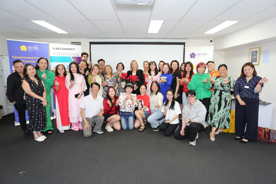 Group of people posing for a photo in an indoor setting with a backdrop featuring logos of AVWA and RECONNECT, some holding red poinsettias. 