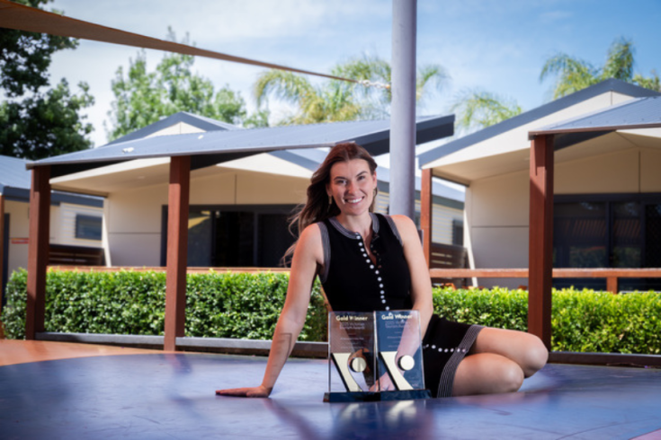 Woman lying on a deck showing her awards