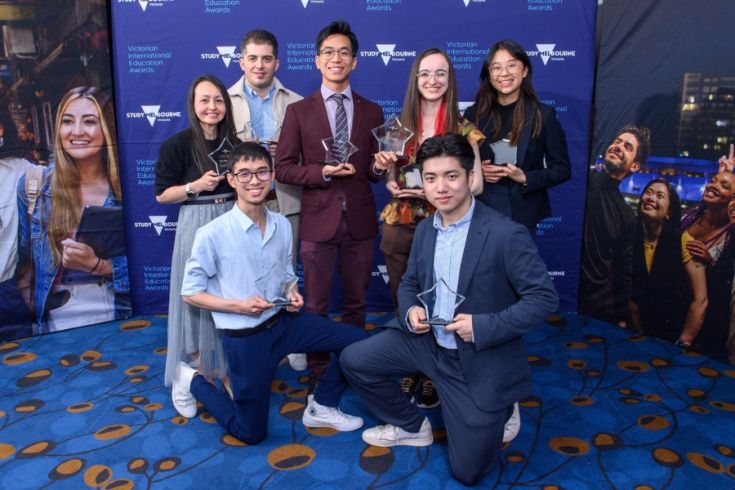 A group of 7 people smile and hold awards in front of a backdrop with Study Melbourne and Victorian International Education Awards logos.