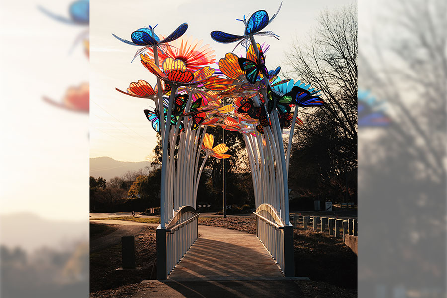 The Colour Bridge at Porepunkah, showing the transformation of the Roberts Creek Bridge through an installation of brightly coloured flowers and butterflies creating and arch over the bridge. 