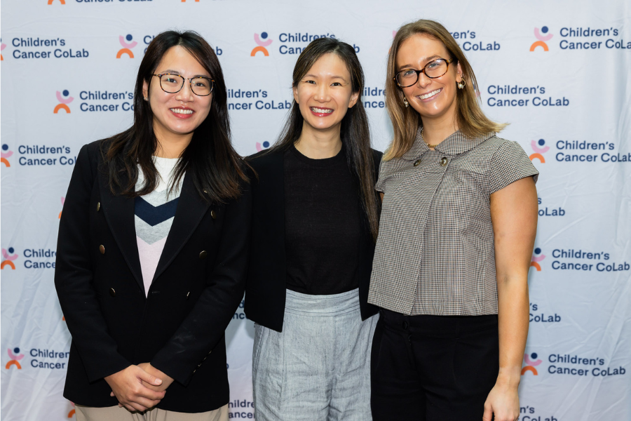 Three people smiling in front of a Children's Cancer CoLab backdrop.