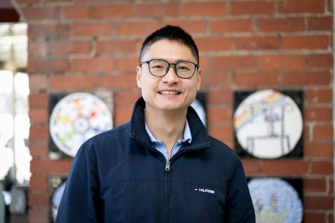 Jack Zhou smiling, wearing a blue jumper